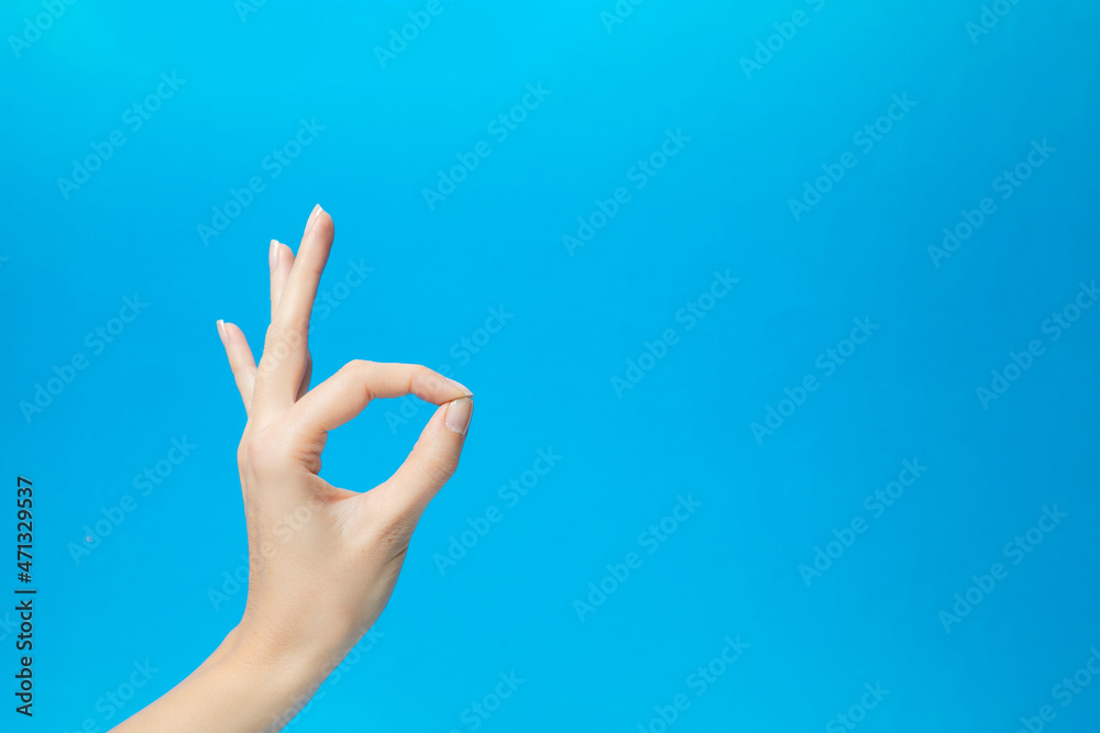Woman's hand making sign for perfect. Like Italian. great job. Blue background.