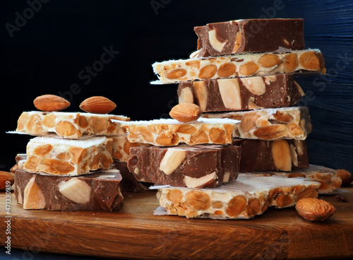 Chocolate turron with almonds, hard alicantian turron on a vintage wooden board. Close-up