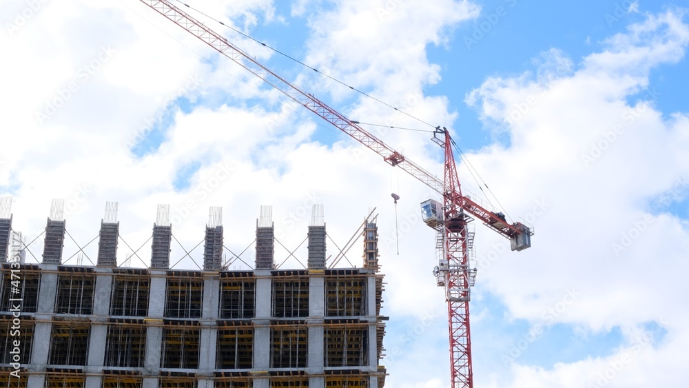 Construction industry. High rise building under construction and construction crane up to the sky. Housing construction, apartment building in the city, mortgage