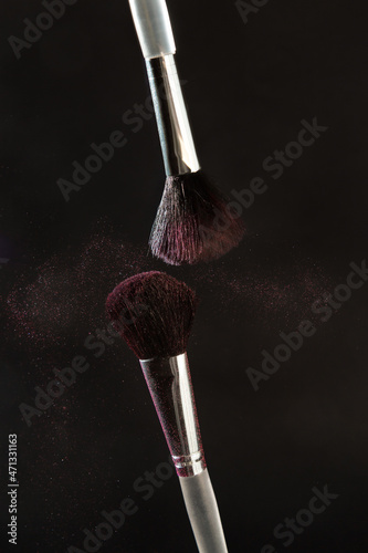 Cosmetic brushes in motion on a dark background 