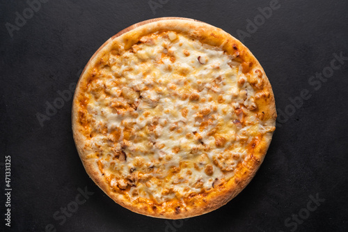 Delicious traditional homemade pizza with tomato, pepper, sausage, cheese on a black background.