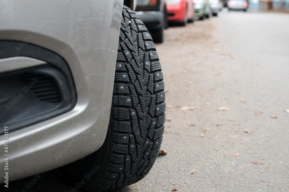 Front wheel of a car with spikes for a winter road close-up.