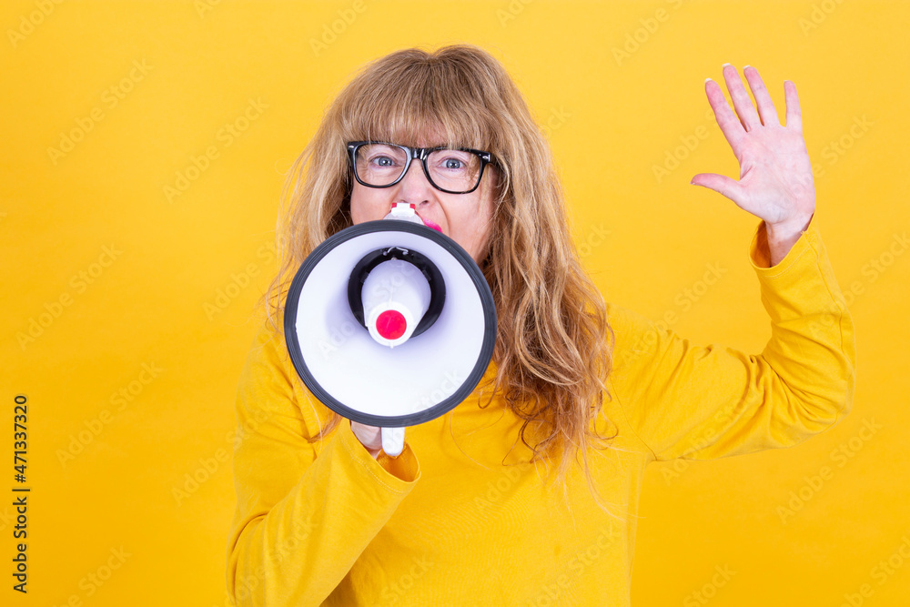 Fototapeta premium mature woman yelling with megaphone with yellow background