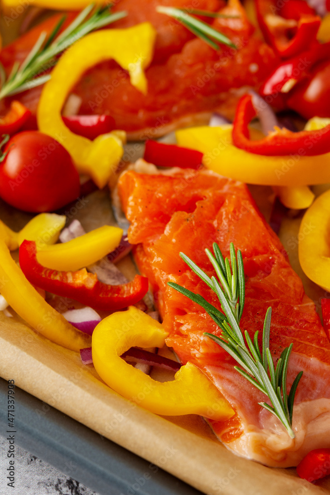 Baking sheet with cooked fish for baking, red fish Arctic char with tomatoes and peppers and rosemary on a baking sheet close-up Baking sheet with cooked fish for baking, red fish Arctic char with tomatoes and peppers and rosemary on a baking sheet close-up