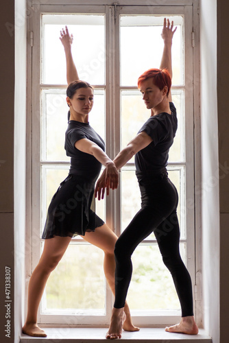 Two caucasian dancers performing on the window. Beautiful young ballet dancers