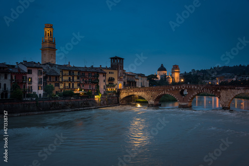 Buildings of the old town along the bank of the Adige river and the famous Stone Bridge (Ponte di Piettra) at night, Verona, Veneto Region, Italy