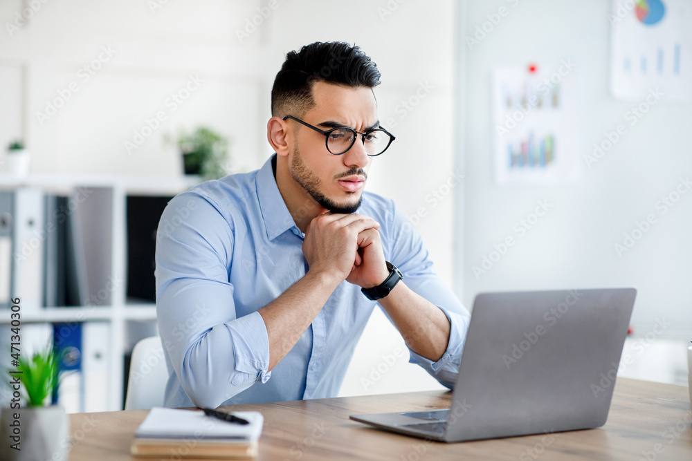 Stressed Arab man using laptop, having problem performing work task, making mistake in business project at office Stressed Arab man using laptop, having problem performing work task, making mistake in business project at office