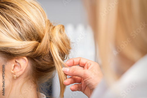 Close-up hairdresser styling blonde hair on the back of the head in a beauty salon