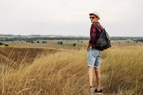 man with a backpack on a country walk on a summer day. Young people hiking in the countryside, outdoors at sunset © Shopping King Louie