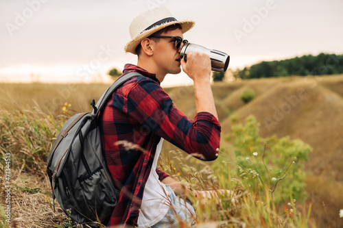 hiker sits on the top of the mountain, man with a cup of coffee sits on a rock with a view of the nature around