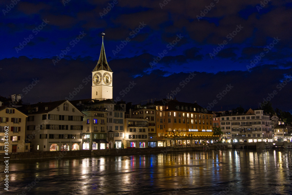 River Limmat and Limmatquai with illuminated church of Sankt Peter in the background