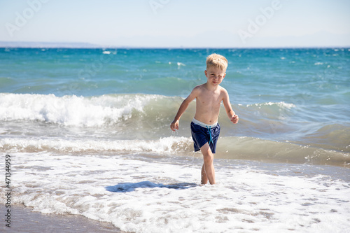 Cute little boy playing on the beach by the sea, he is happy. Concept summer vacation, rest, fun.