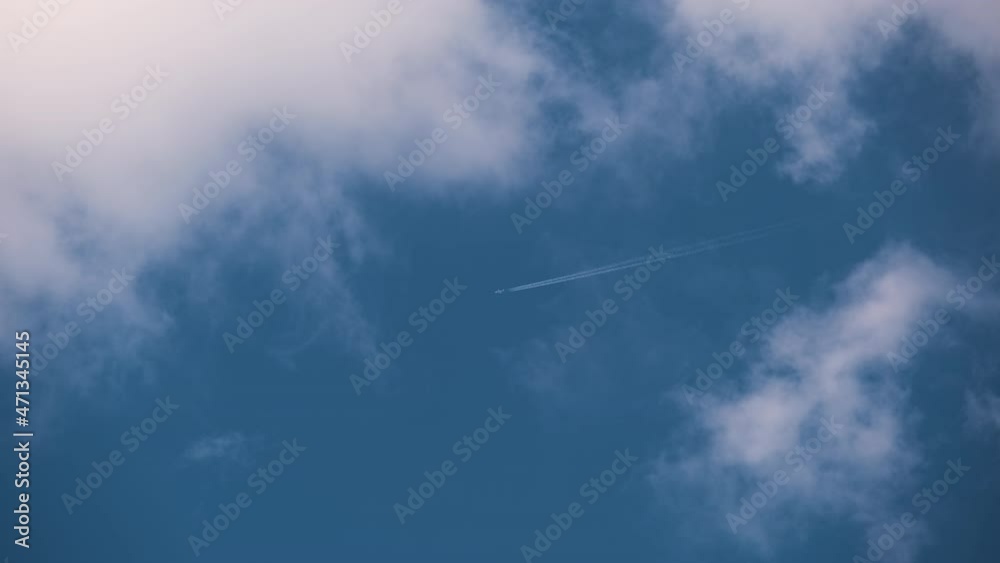 Distant passenger jet plane flying on high altitude on blue sky with white clouds leaving smoke trace of contrail behind. Air traveling concept Distant passenger jet plane flying on high altitude on blue sky with white clouds leaving smoke trace of contrail behind. Air traveling concept