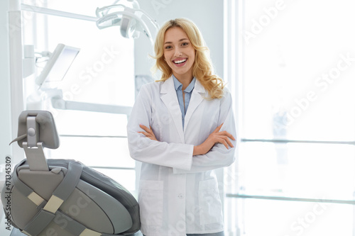 Young blonde woman dentist posing at dental cabinet