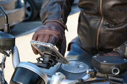 Close up of a person using mobile phone on motorbike