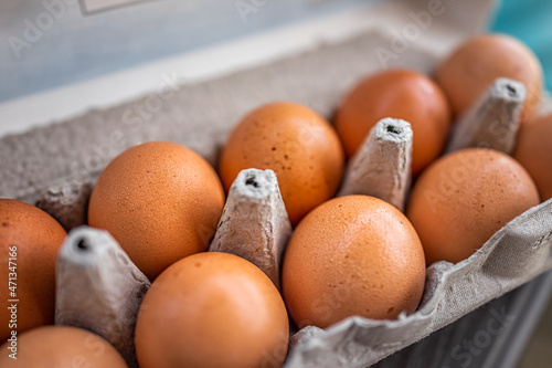 Closeup macro of pasture raised farm fresh dozen brown eggs store bought from farmer in carton box container with speckled eggshells texture photo