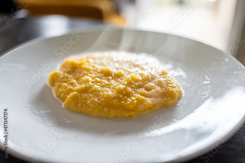 Cooked yellow southern american corn grits on plate as breakfast porridge with hot steam rising and texture of healthy cereal photo