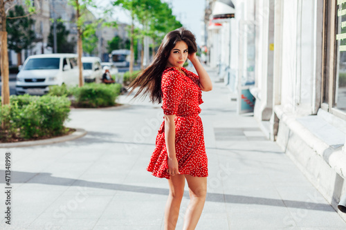 beautiful woman in a summer red dress walks down the street