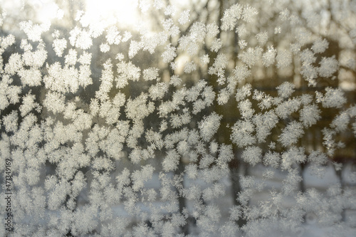 Frosty pattern on the window glass in the rays of the sun. Selective focus. Winter background.