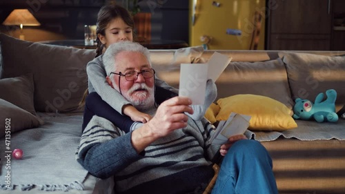 Old man chatting with granddaughter looking at photo album photo