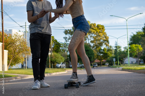 unrecognizable couple skateboarding on an asphalt street in the park