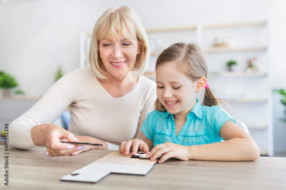 Happy mature woman and granddaughter solving jigsaw puzzle Happy mature woman and granddaughter solving jigsaw puzzle