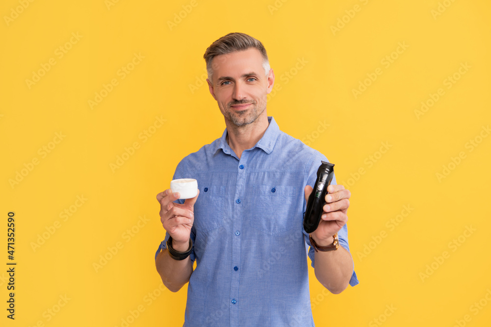 mature man with grizzled hair hold electric razor and cream on yellow background, personal care mature man with grizzled hair hold electric razor and cream on yellow background, personal care