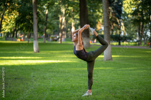 beautiful young girl exercising in the park, yoga, relax fitness, nataradjasana photo