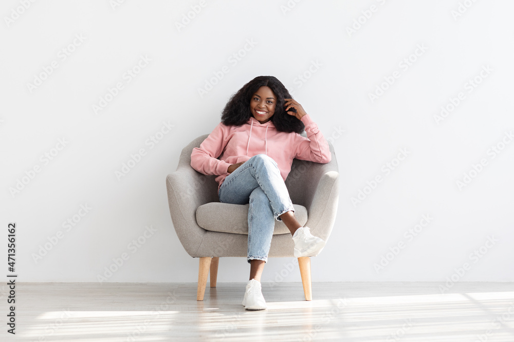 Attractive young black woman resting in arm chair at home