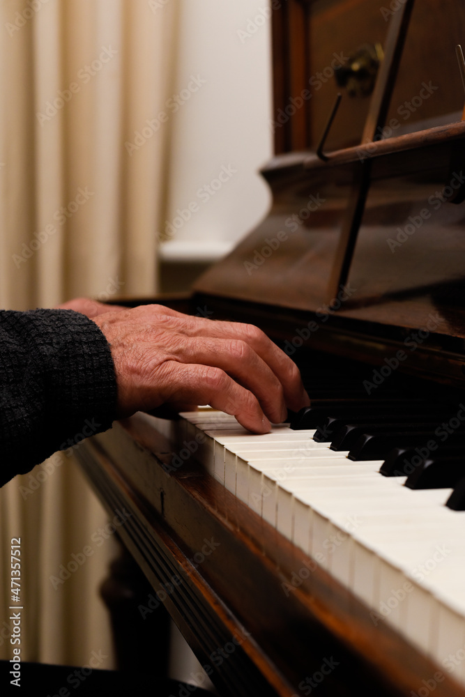 Mature male hands playing piano with focus on hands and keyboard