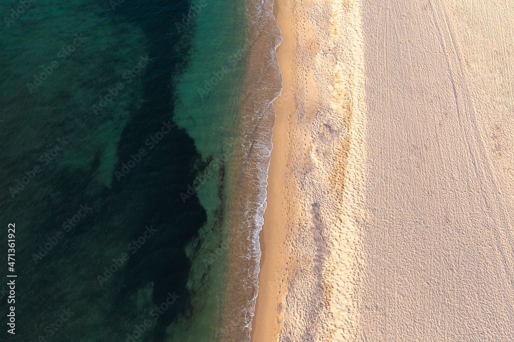 Aerial top down view of beautiful white sand beach bathed by clear turquoise seawater.