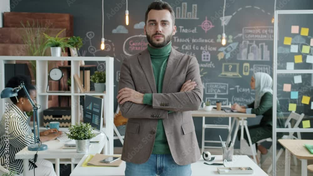 Slow motion portrait of ambitious guy in stylish outfit standing in office with arms crossed and looking at camera. Business and employment concept. Slow motion portrait of ambitious guy in stylish outfit standing in office with arms crossed and looking at camera. Business and employment concept.