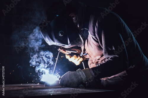 Welder welding on a table in a factory with smoke
