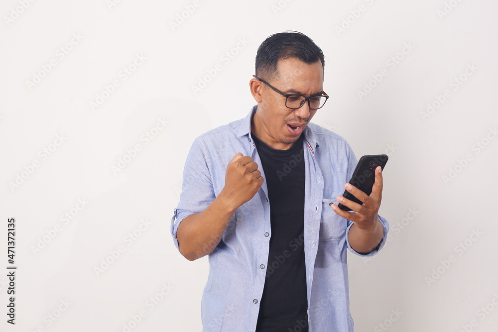 Joyful Asian man while looking at mobile phone. Isolated on white background Joyful Asian man while looking at mobile phone. Isolated on white background