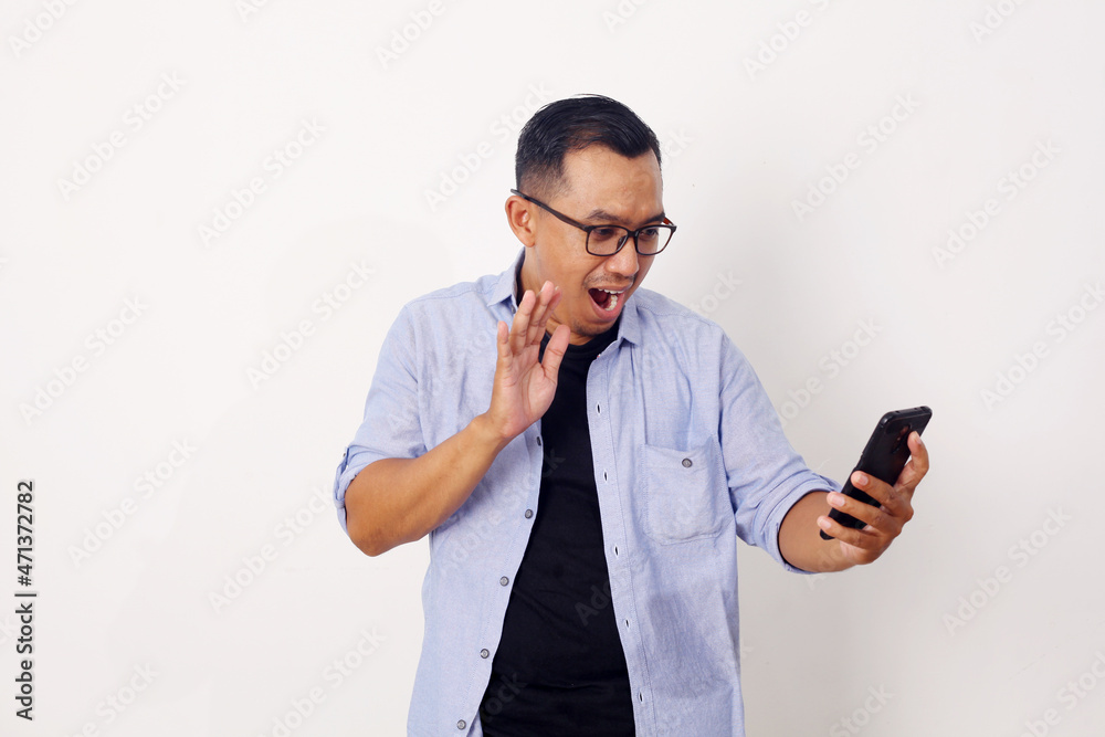 Shocked Asian man while looking at mobile phone. Isolated on white background Shocked Asian man while looking at mobile phone. Isolated on white background