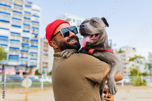 Photography portrait of happy man in red hat and sunglasses with american terrier in dogs wa