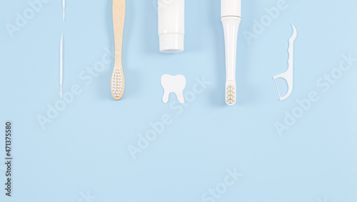 A set of toothbrushes  toothpicks  dental floss and toothpaste on pale blue.