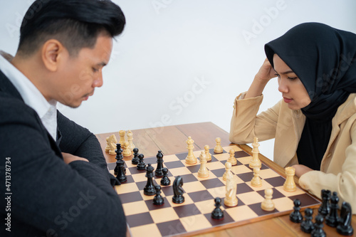 Woman in headscarf getting confused while playing chess