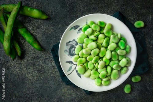 green broad beans in a white plate against dark background