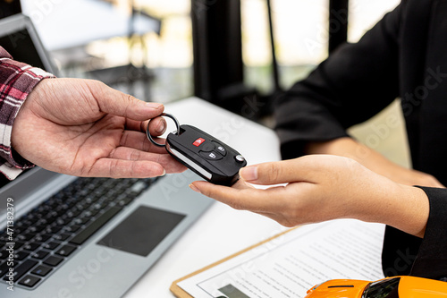 Person holding the car key to the car rental company employee, the customer who has completed the rental car has returned the car to the company and pre-checked, car rental service concept.