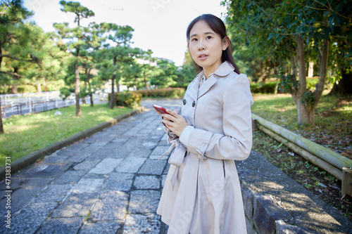 公園で携帯電話を見るアジア人女性