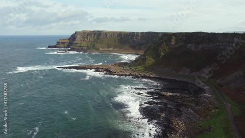 Aerial view of the Giant's Causeway on a sunny day, County Antrim, Northern Ireland. Flying away from the Causeway along the coast.