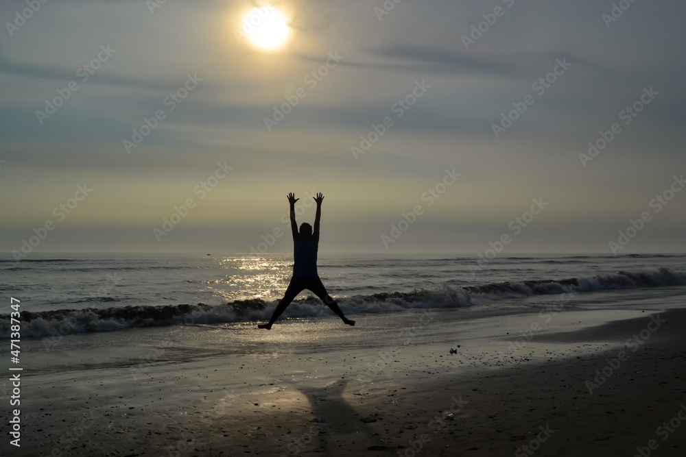 Silhouette of a man jumping on the shore of a beach at sunset Pacific Ocean  Peru