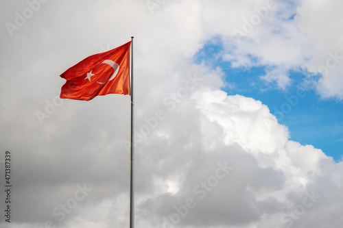 Waving turkish flag on flagpole. Blue sky and storm clouds.