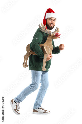 Walking man in Santa hat and with wooden deer on white background © Pixel-Shot