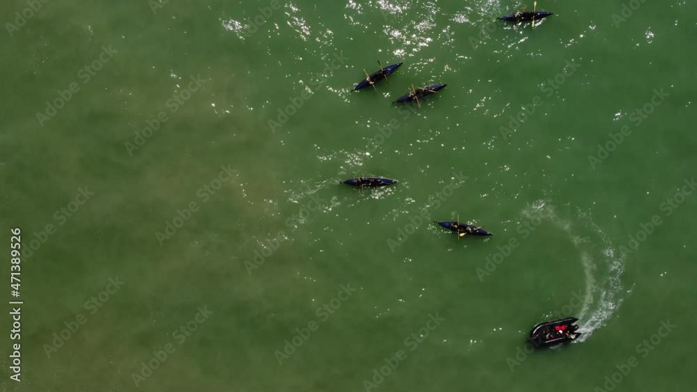 Aerial top down shot of black boats of professional rowing team practicing on natural ocean during summer Aerial top down shot of black boats of professional rowing team practicing on natural ocean during summer