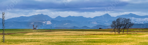 Canadian Rocky Mountain range beautiful rural Alberta prairies and grassland panoramic landscape. Oil pump jack in farmland