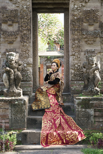 Woman sitting wearing traditional Balinese kebaya with long woven cloth