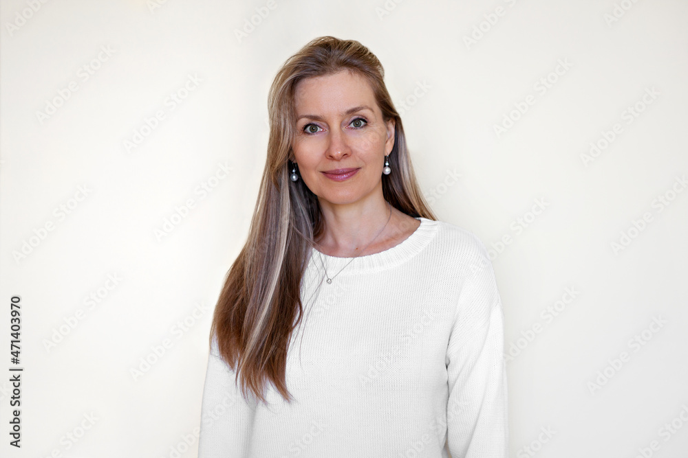 Obraz premium Portrait of pleased Caucasian woman with long hair, forty years old, looking into the camera, wearing bright clothes, isolated on white background. Beautiful Model looks into the camera