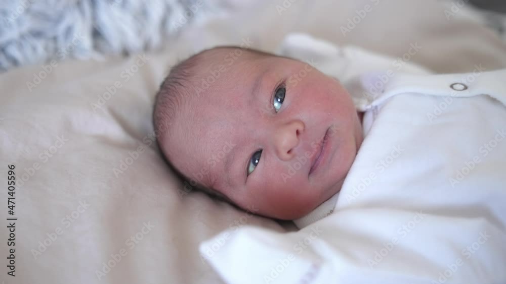 Lovely newborn baby portrait. Face of an infant baby laying on a bed. Hungry little child looking for mother. Cute little child Lovely newborn baby portrait. Face of an infant baby laying on a bed. Hungry little child looking for mother. Cute little child